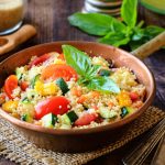 Cous cous di verdure estivo: ricetta leggera e veloce 1 padella con manico piena di cous cous di verdure e foglie di menta