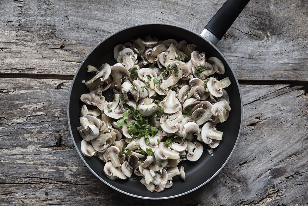 Risotto ai funghi: primo piatto cremoso e gustoso, pronto in pochi passaggi 4 in primo piano in una padella antiaderente dei funghi tagliati e del prezzemolo