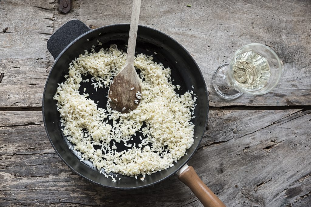 Risotto ai funghi: primo piatto cremoso e gustoso, pronto in pochi passaggi 5 in primo piano una casseruola con del riso che viene tostato con del vino bianco