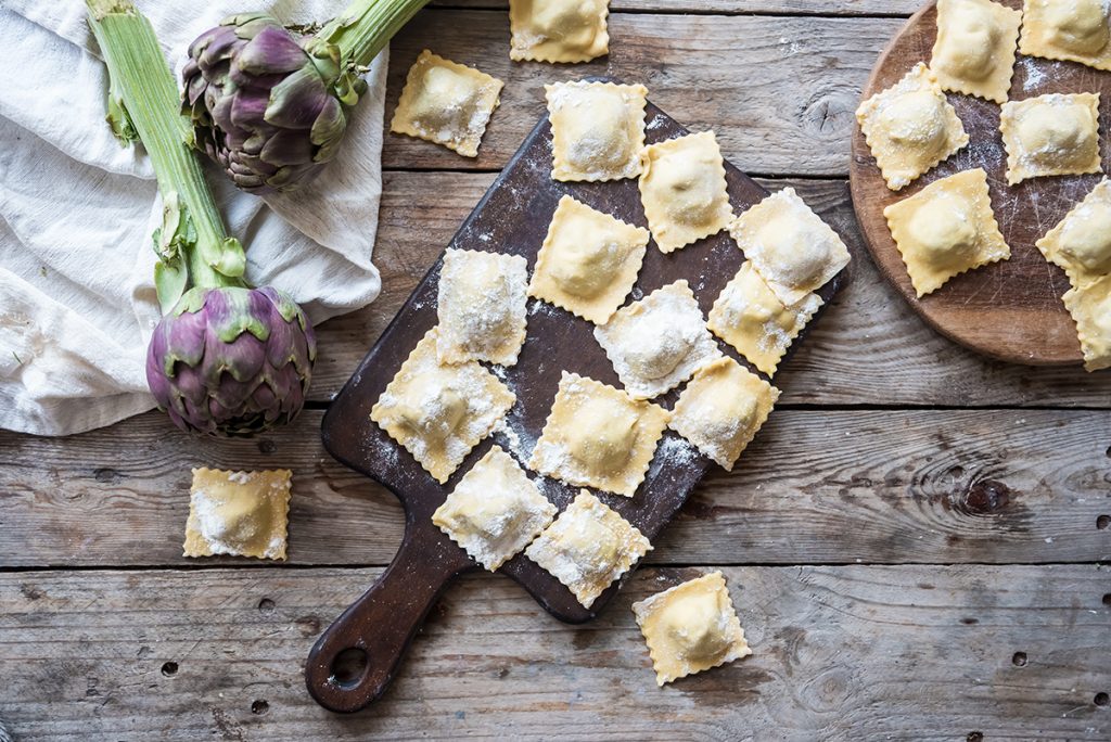 Ravioli di ricotta e carciofi 9 su base di legno tagliere rettangolare e tondo con tanti ravioli quadrati