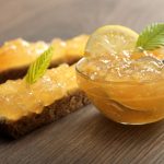 Marmellata di limoni: facile e veloce da fare in casa 1 su base di legno una ciotola di vetro piena di marmellata di limoni e due fette di pane con marmellata di limoni spalmata sopra