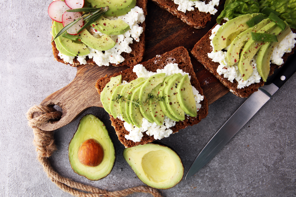 Avocado: su tagliere di legno avocado a fette e un avocado tagliato a met&agrave;