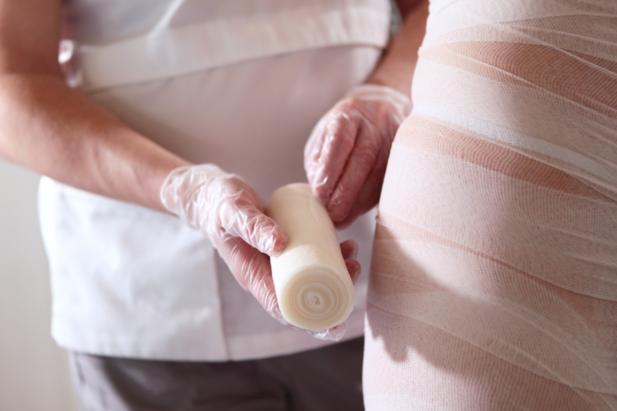 Come avere delle belle gambe: allenamenti, esercizi, cosa mangiare e trattamenti estetici 2 donna dall'estetista che si fa mettere bendaggi anticellulite per avere delle belle gambe
