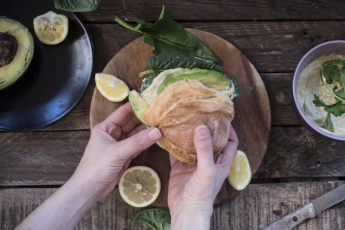 Ricette con panini: 21 idee sfiziose per farcire i tuoi panini 5 due mani finiscono di preparare un panino tondo farcito con hummus avocado e spinaci
