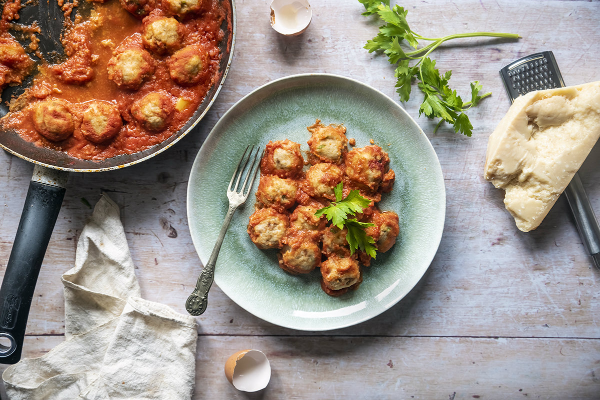 Pane fatto in casa: ricette genuine e semplici da provare 11 un piatto con delle polpette accanto a una padella di polpette, parmigiano e grattugia