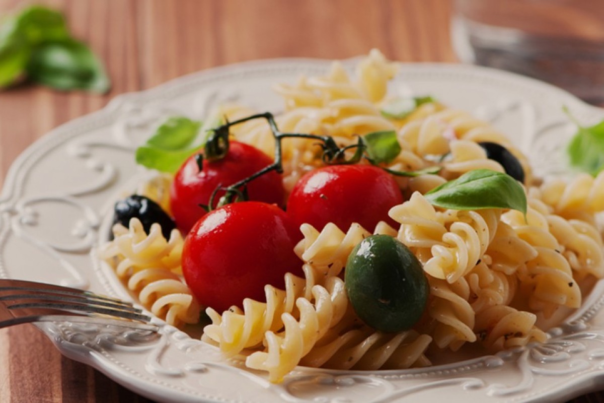 Pasta fredda: 15 ricette veloci da preparare 1 una scodella bianca con fusilli, pomodorini e foglie di basilico