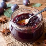 Marmellata di prugne fatta in casa: ricetta senza zucchero facile e genuina 2 in primo piano su un tavolo di legno un barattolo di vetro con la marmellata di prugne e un cucchiaino