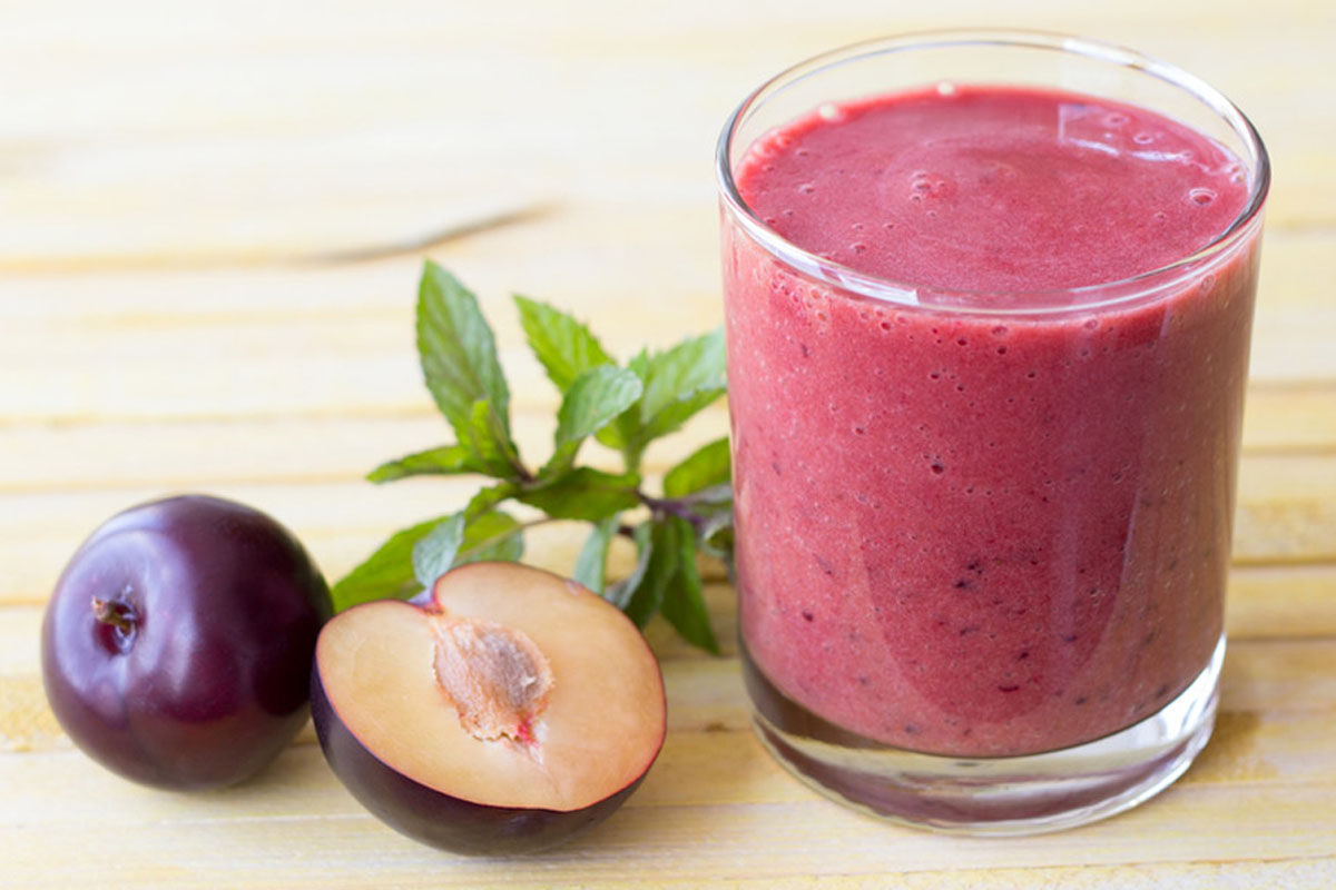 Prugne o susine: calorie, proprietà, benefici e usi in cucina 4 un bicchiere di smoothie alle prugne con accanto alcuni frutti