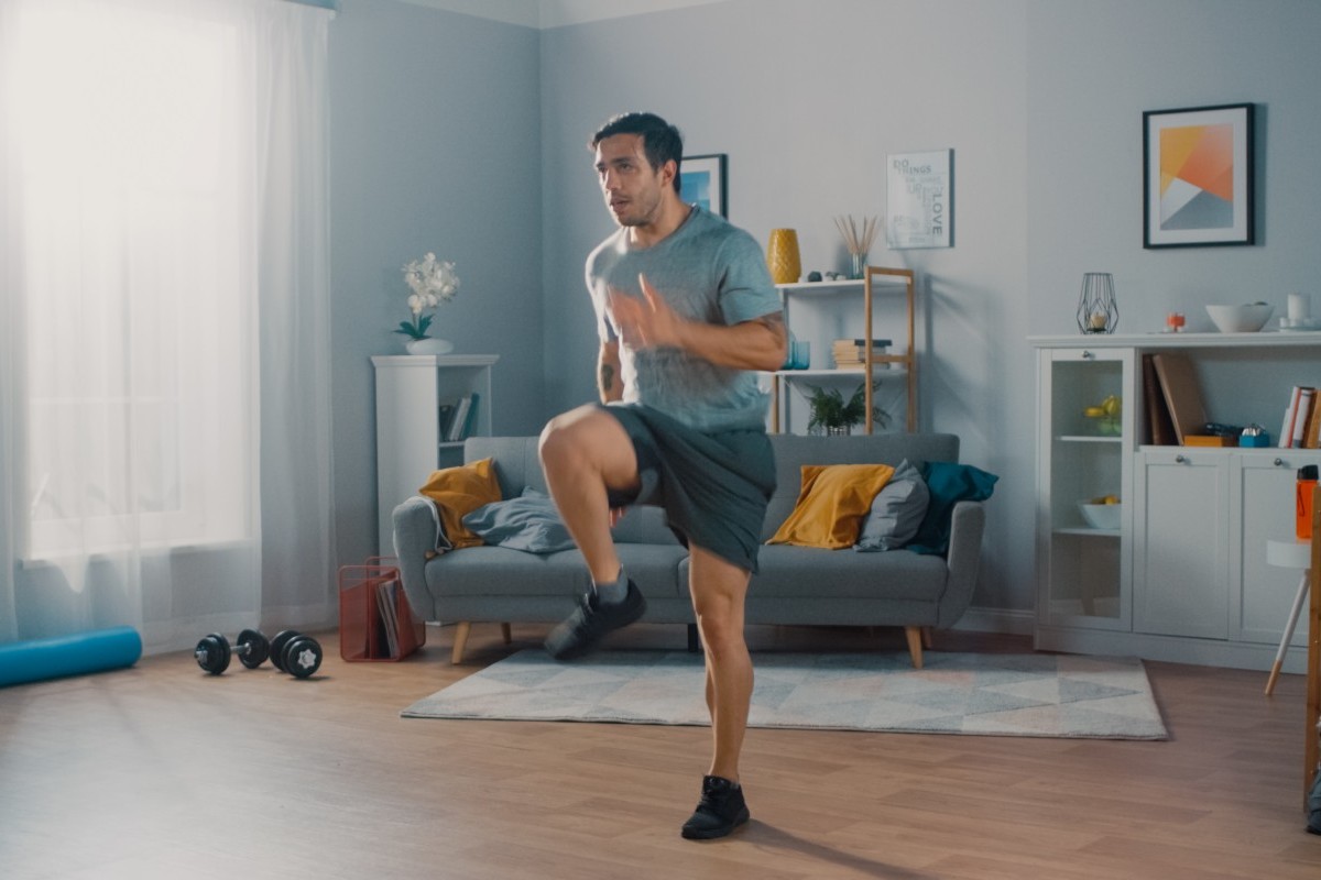 Un uomo nel soggiorno di casa pratica un programma di walk at home
