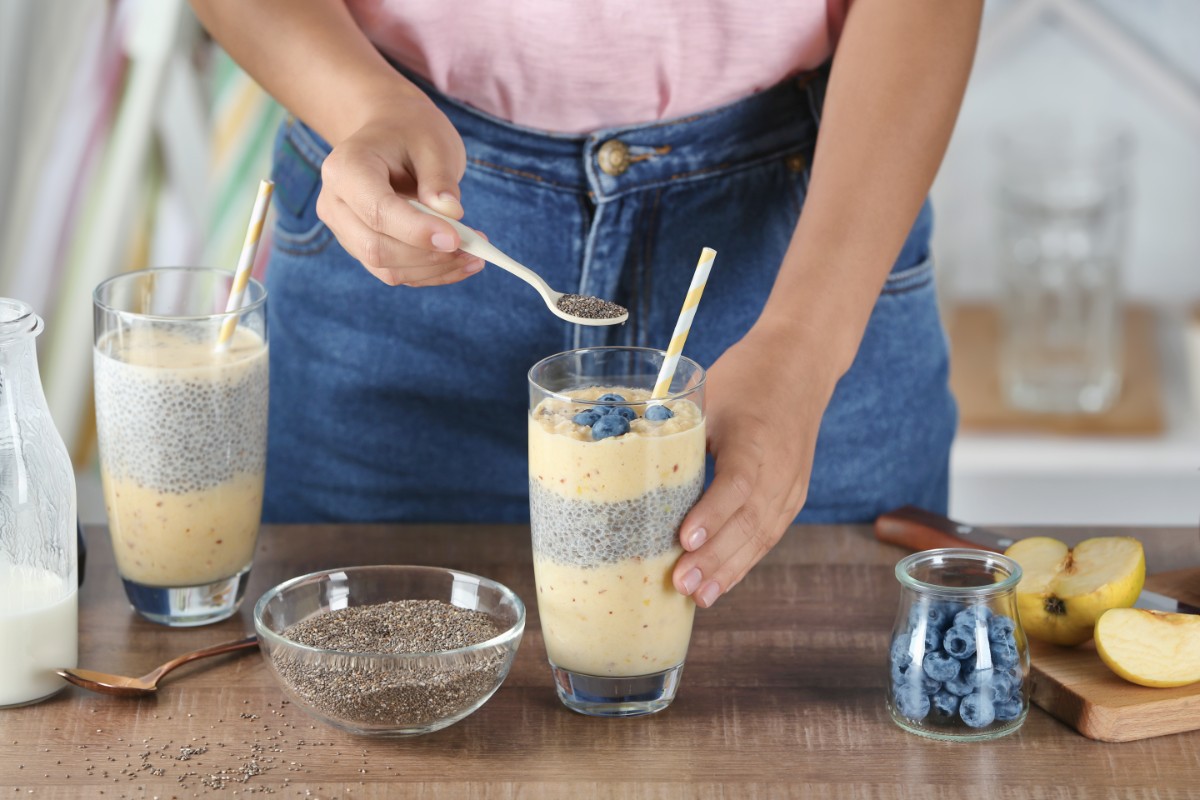 Semi di chia: proprietà e benefici, come mangiarli, ricette e controindicazioni 5 una donna che aggiunge semi di chia a un frullato