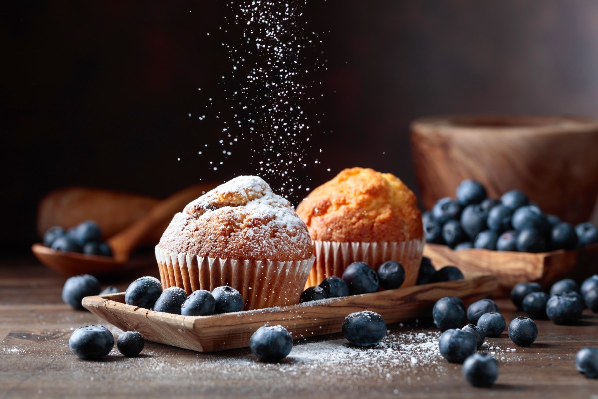 Mirtilli: proprietà, calorie, controindicazioni e ricette 3 un paio di muffin ai mirtilli con alcuni mirtilli sparsi accanto