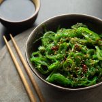 Insalata di alghe wakame superfood: la ricetta passo passo 1 una ciotola con dentro l'alga wakame e acconto due bacchette giapponesi