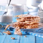 Chiacchiere senza glutine: croccanti e facili da preparare 1 Dolci di carnevale: su tavola azzurra un piatto con le chiacchiere al forno e un vasetto di zucchero accanto