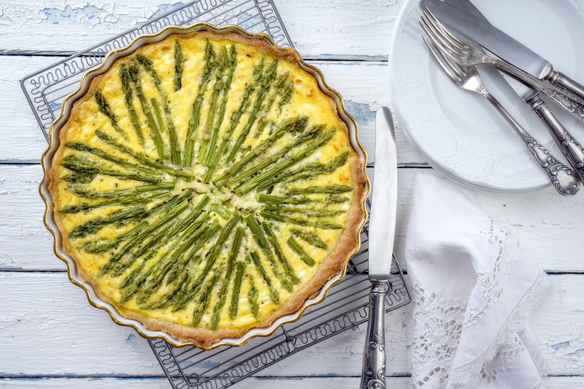 Torte salate: 29 ricette veloci e leggere per tutti i gusti 9 una teglia rotonda con una quiche con asparagi, coltello e posate
