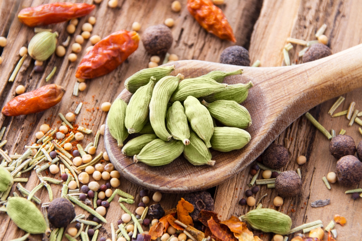 Cardamomo: a cosa serve, proprietà e usi 3 Un cucchiaio di legno con sopra alcuni semi di cardamomo