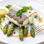 Nasello in padella: ricetta leggera e facile 1 piatto bianco con due filetti di nasello in padella accompagnati da asparagi