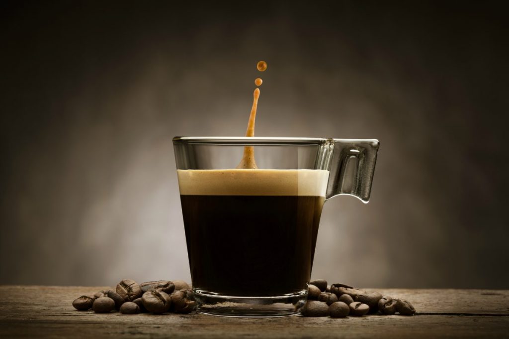 Bere caffè a stomaco vuoto fa male? Risponde il nutrizionista 1 bere caffè a stomaco vuoto: una tazzina di caffè in vetro con accanto alcuni chicchi di caffè