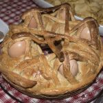 Casatiello napoletano: la torta salata di Pasqua in versione leggera 1 su tovaglia a quadri un casatiello napoletano con uova intere con guscio