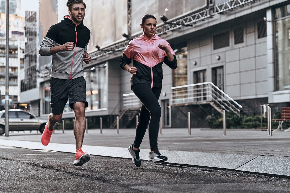 Programma allenamento corsa: come allenarti e tabelle running per principianti e esperti 1 in città, un uomo e una donna che corrono per strada seguendo un programma allenamento corsa