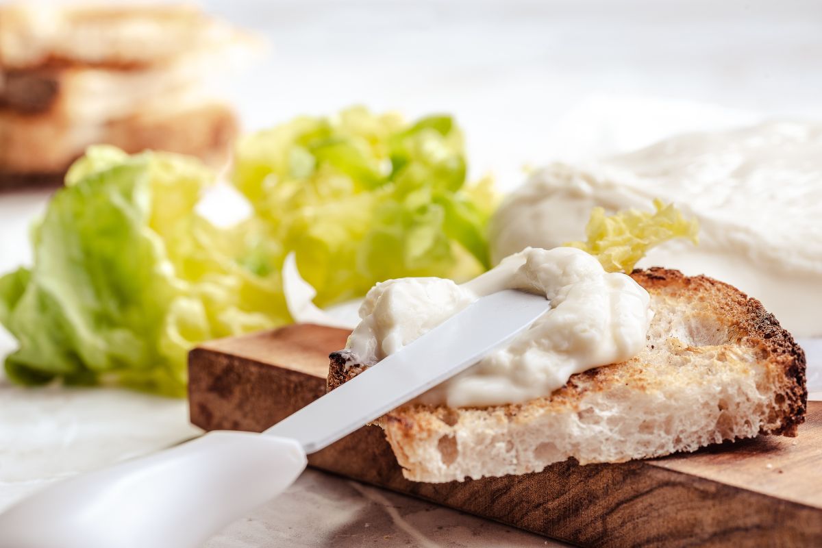 Formaggi: tipologie, quali sono, proprietà e benefici e usi a dieta 2 Una fetta di pane con sopra del formaggio splamabile e un coltello in plastica