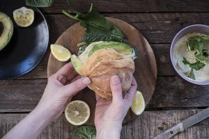 Panino vegan con hummus di ceci, avocado e spinaci freschi