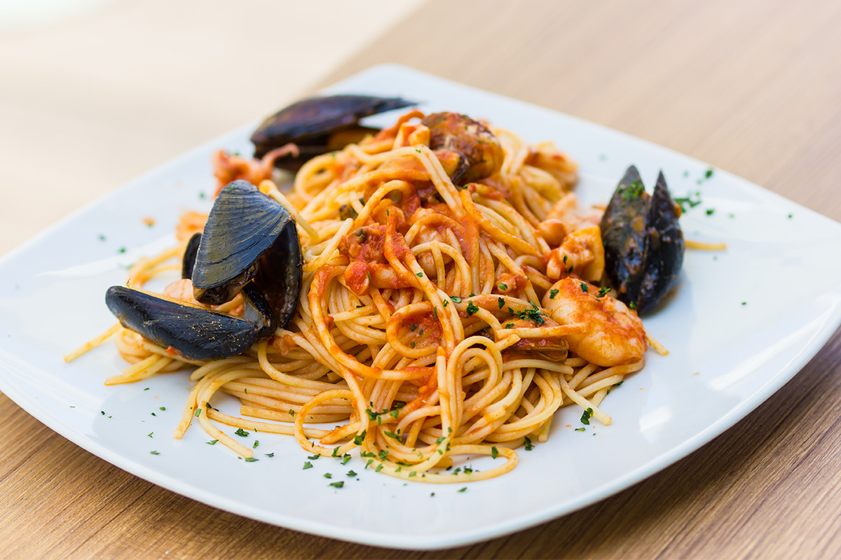 Sughi per pasta fatti in casa: ricette veloci e sane piene di gusto 1 piatto bianco quadrato con porzione di spaghetti allo scoglio