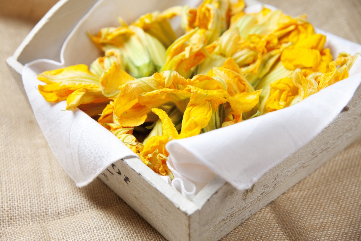 Fiori di zucca fritti senza pastella croccanti e leggeri 4 vassoio di legno con tovagliolo bianco che contiene fiori di zucca per preparare fiori di zucca fritti