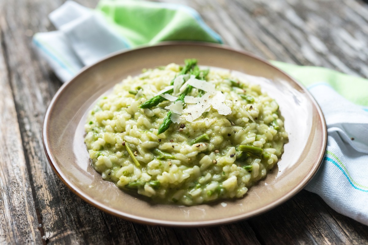 su base di legno piatto tondo grigio con risotto agli asparagi