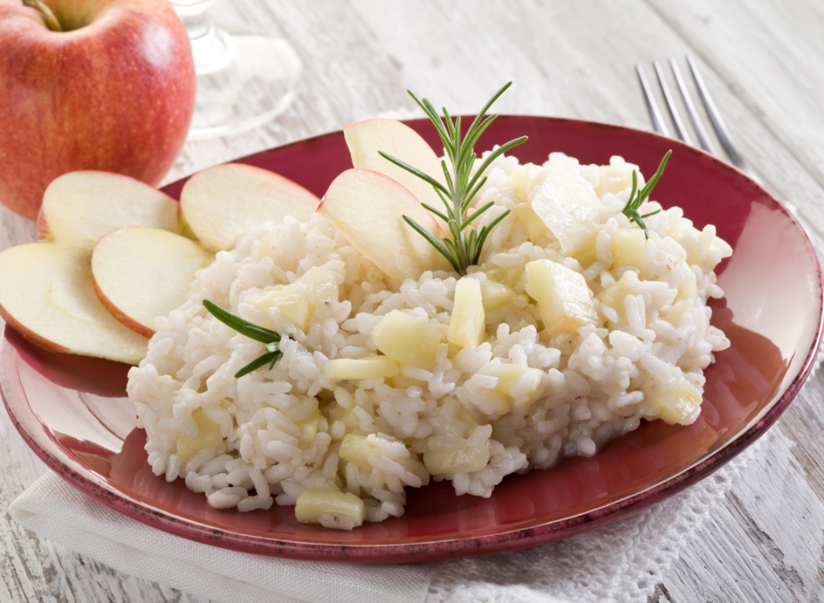 Risotto: ricette semplici e veloci, dai grandi classici alle versioni innovative 11 su tovaglia bianca piatto rosso con il risotto alle mele e una mela sul fondo