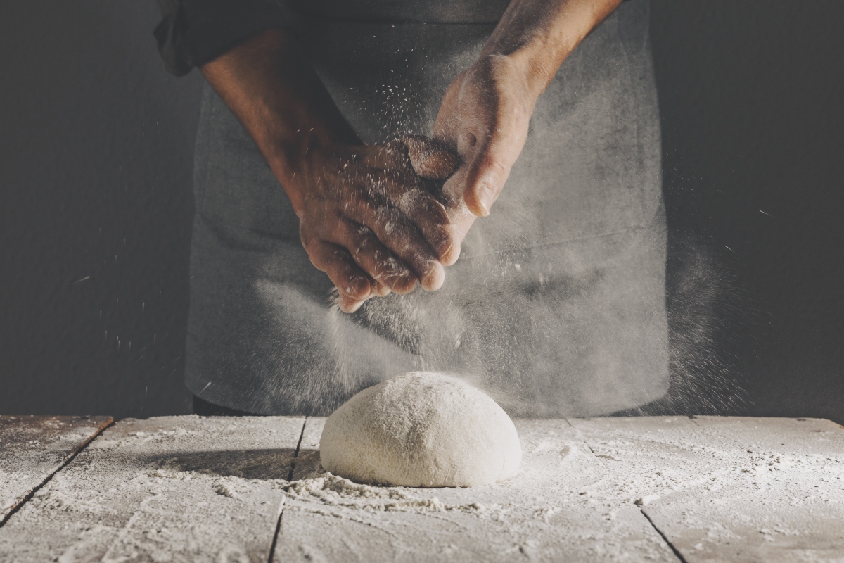 Glutine: cos’è, a cosa serve, alimenti gluten free e intolleranze 1 Due mani in primo piano che impastano farina con glutine