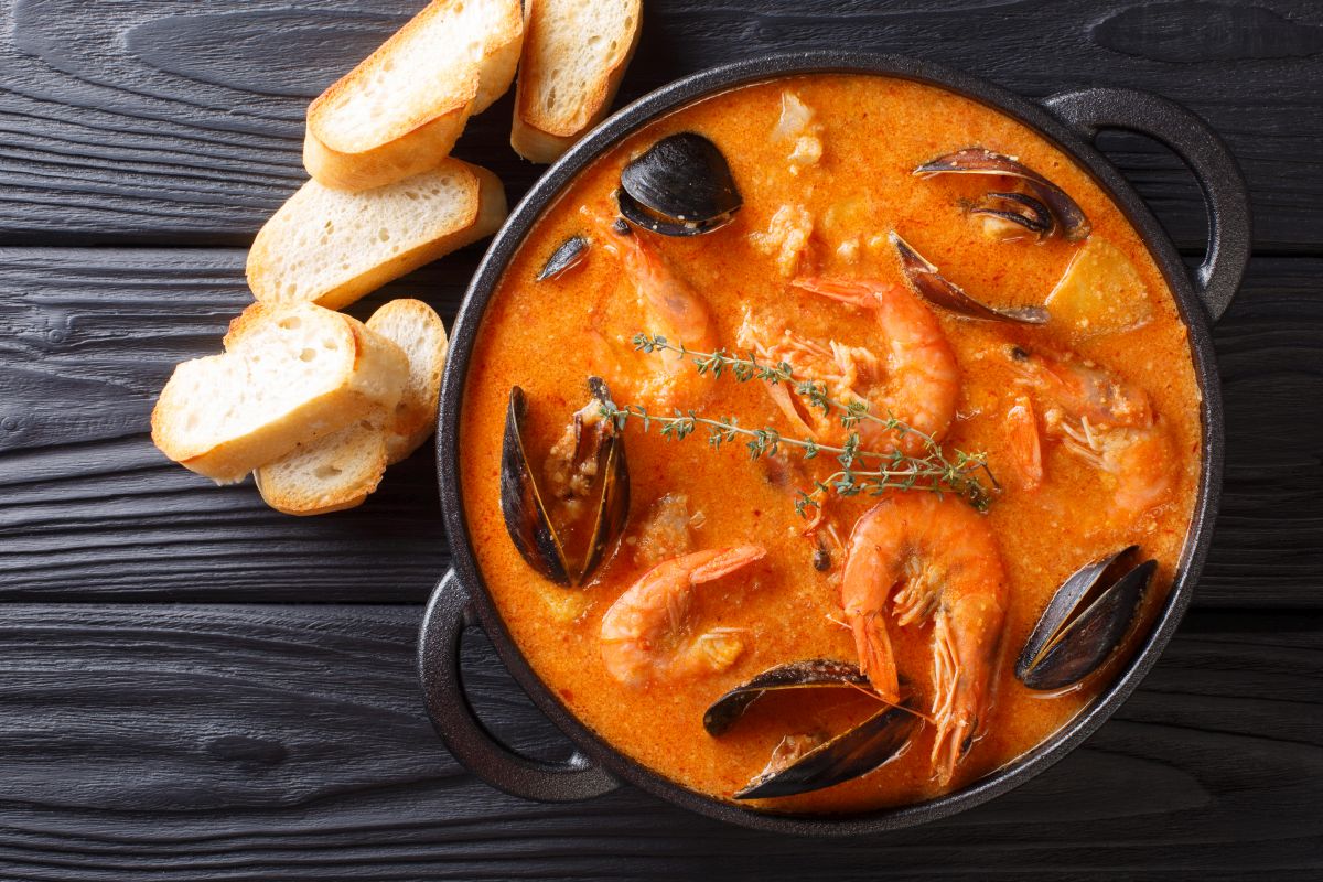 Piatti unici: le ricette veloci, vegetariane, estive e invernali 21 un piatto di zuppa di pesce con alcune fettine di pane accanto