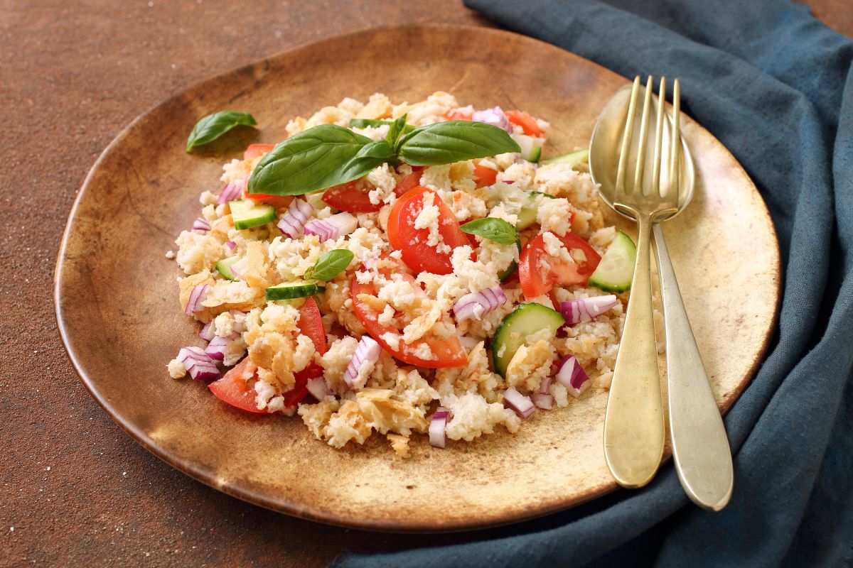 un piatto di legno tondo con una porzione di panzanella fresca