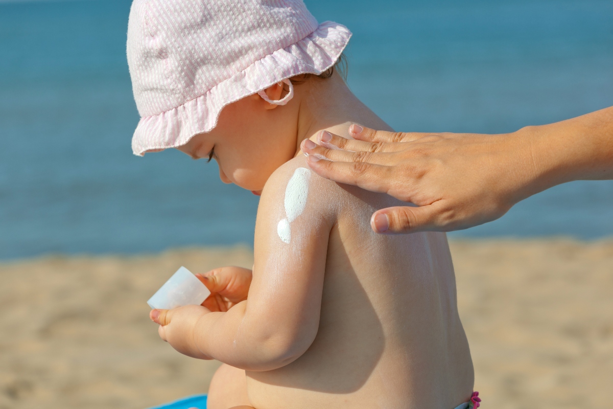 Eritema solare: sintomi, rimedi e creme per proteggere la pelle 6 una mamma che spalma la crema sulla schiena di un bambino piccolo per evitare l'eritema solare