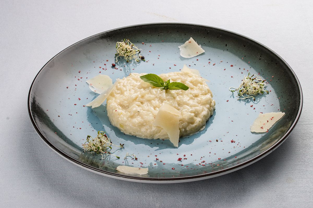 Risotto: ricette semplici e veloci, dai grandi classici alle versioni innovative 1 piatto tondo basso e scuro con al centro una porzione di risotto e erette