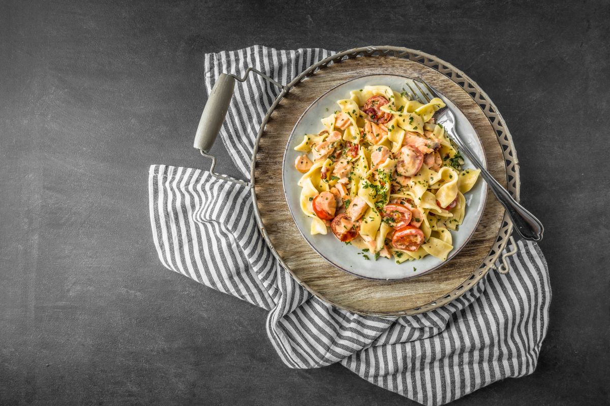Pasta al salmone, un primo piatto veloce e cremoso 4 canovaccio e piatto grigio e bianco con pasta al salmone e pomodorini freschi