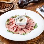 Salsa tonnata: la ricetta sana fatta in casa 1 piatto rotondo bianco con fettine di vitella e al centro una ciotola di salsa tonnata