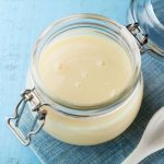 Latte condensato fatto in casa: ricetta facile 1 un barattolo pieno di latte condensato su un piano azzurro