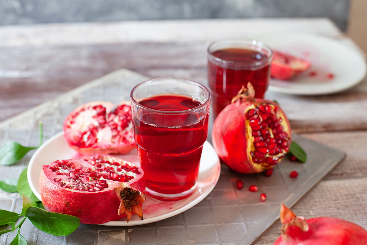 Melagrana: proprietà, benefici, come sgranare il melograno e idee ricette 2 Una melagrana aperta e due bicchieri con succo di melagrana