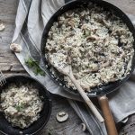 Risotto ai funghi: primo piatto cremoso e gustoso, pronto in pochi passaggi 1 una padella con manico e una ciotola scura piene di risotto ai funghi