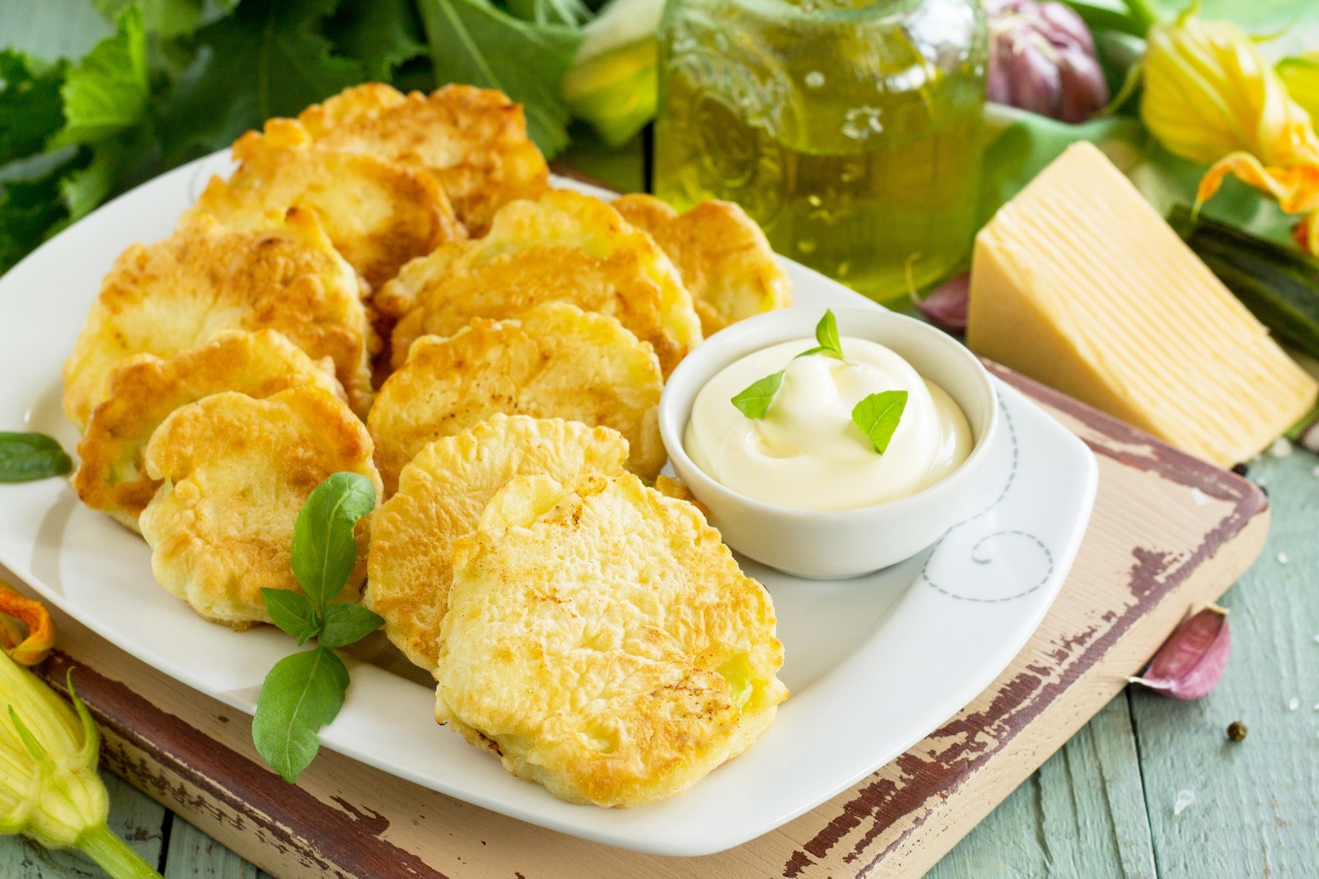 Ricette con cavolfiore: idee facili e creative dall'antipasto al contorno 1 piatto bianco rettangolare con frittelle di cavolfiore e ciotola di salsa