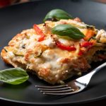 Lasagne con zucchine: la ricetta bianca, sana e squisita 1 primo piano di un piatto nero con una porzione di lasagne con zucchine