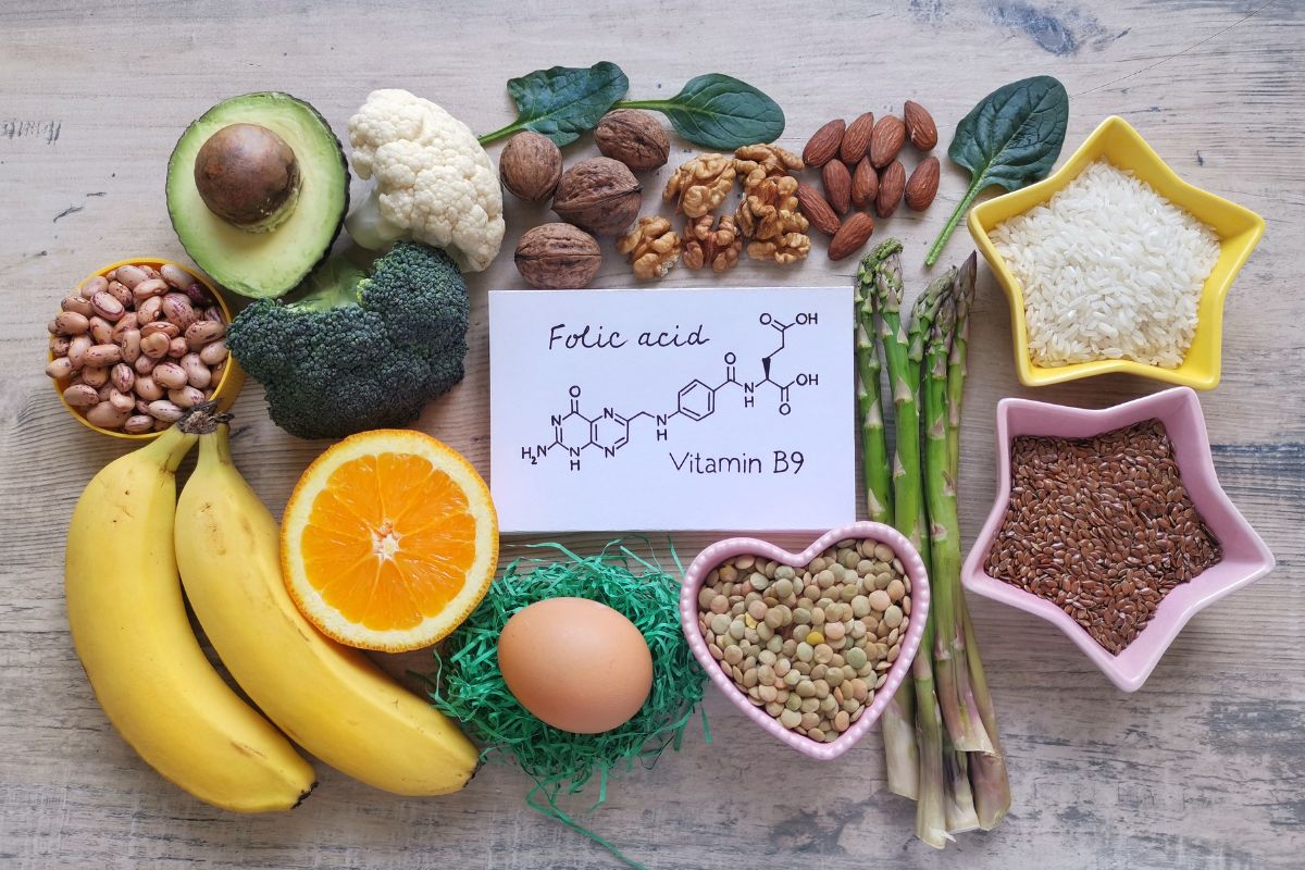 alimenti ricchi di acido folico: alcuni alimenti su un tavolo con al centro un foglio con la formula della vitamina B9