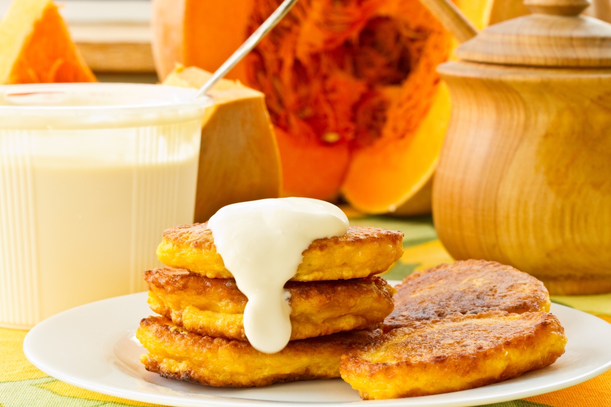 Ricette con la zucca: le migliori idee sane e gustose 19 piatto piano con frittelle di zucca e crema, zucca aspetta sullo sfondo