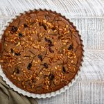 Castagnaccio Toscano: torta genuina e semplice da preparare 1 su tavolo di legno grigio tortiera con castagnaccio e un canovaccio verde militare
