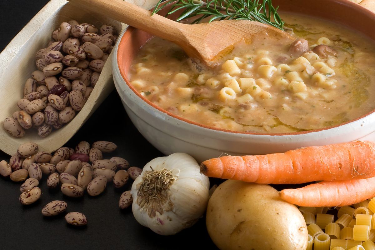 Piatti unici: le ricette veloci, vegetariane, estive e invernali 12 Un piatto di pasta e fagioli con accanto dei fagioli secchi, carota, cipolla e carote