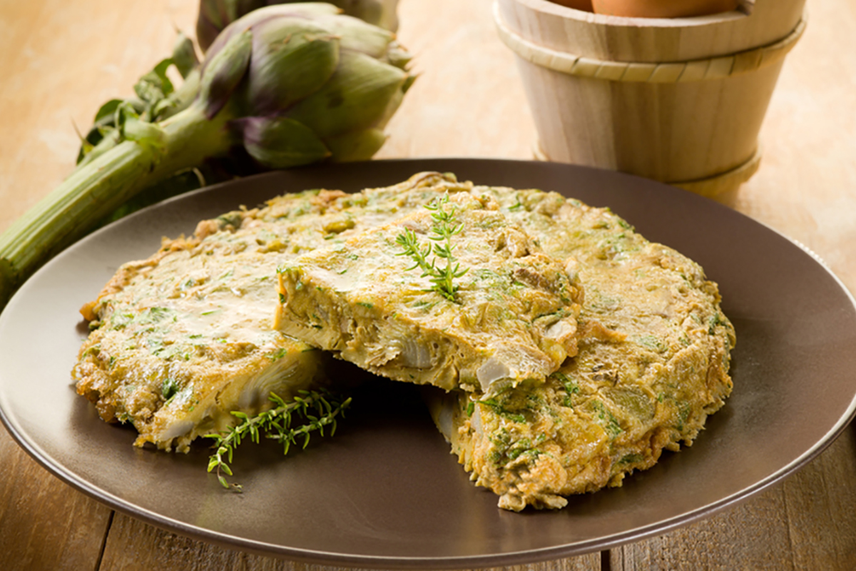 Ricette con carciofi: antipasti, primi, secondi e contorni, dai più facili ai più elaborati 1 piatto tondo con una frittata di carciofi con uno spicchio tagliato