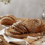 Pane integrale fatto in casa: ricetta facile passo passo 1 In primo piano, su un tavolo di legno chiaro, su un tagliere c'è del pane integrale tagliato a fettine sottili.