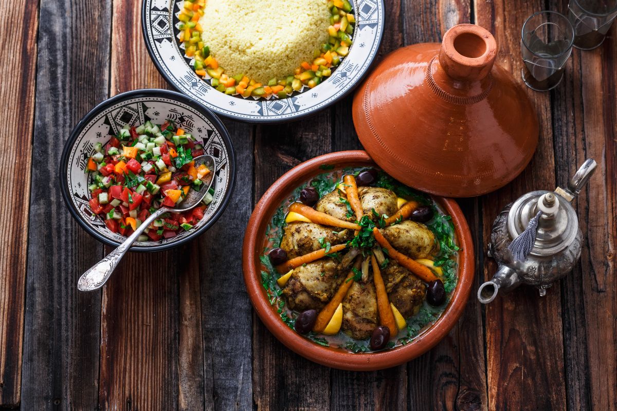 Tajine, la ricetta tradizionale del Marocco 2 su tavolo di legno tajine di pollo dentro la pentola marocchina con accanto una ciotola ingredienti