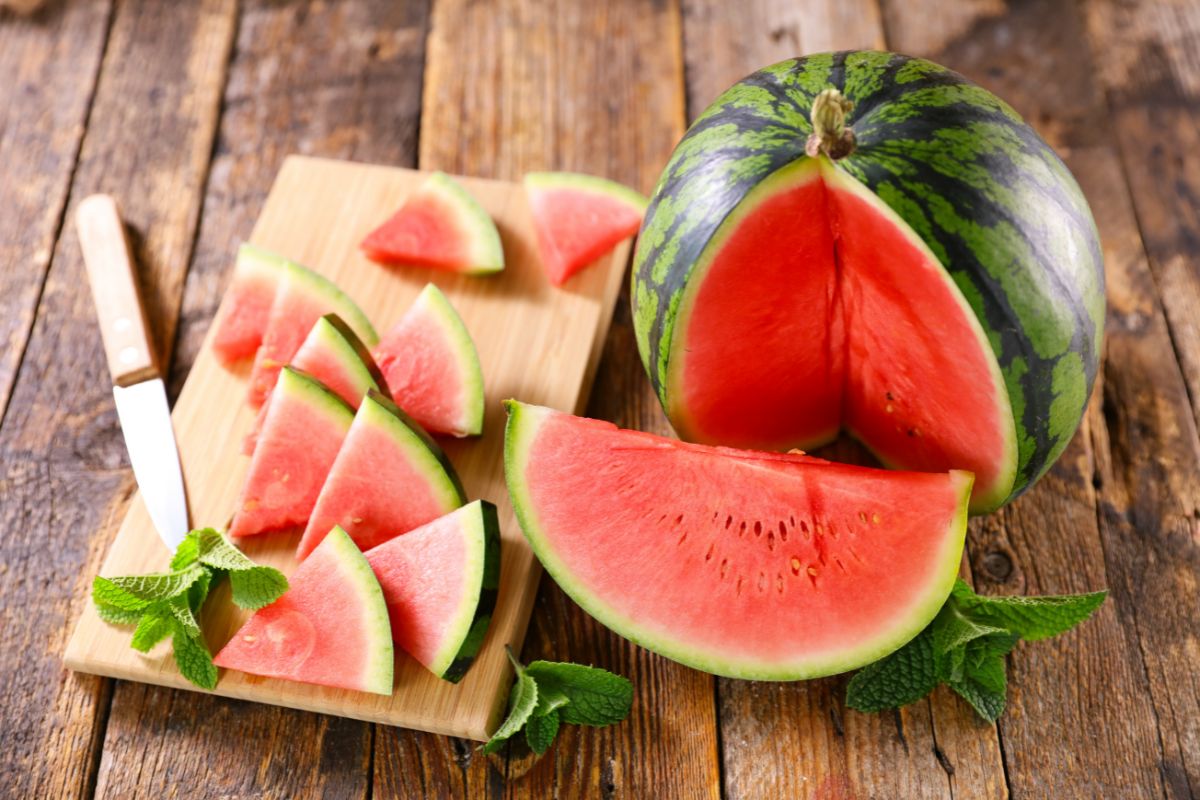 L'anguria fa ingrassare? La verità tra calorie e dieta 2 Un'anguria taglia a metà con alcune fette accanto