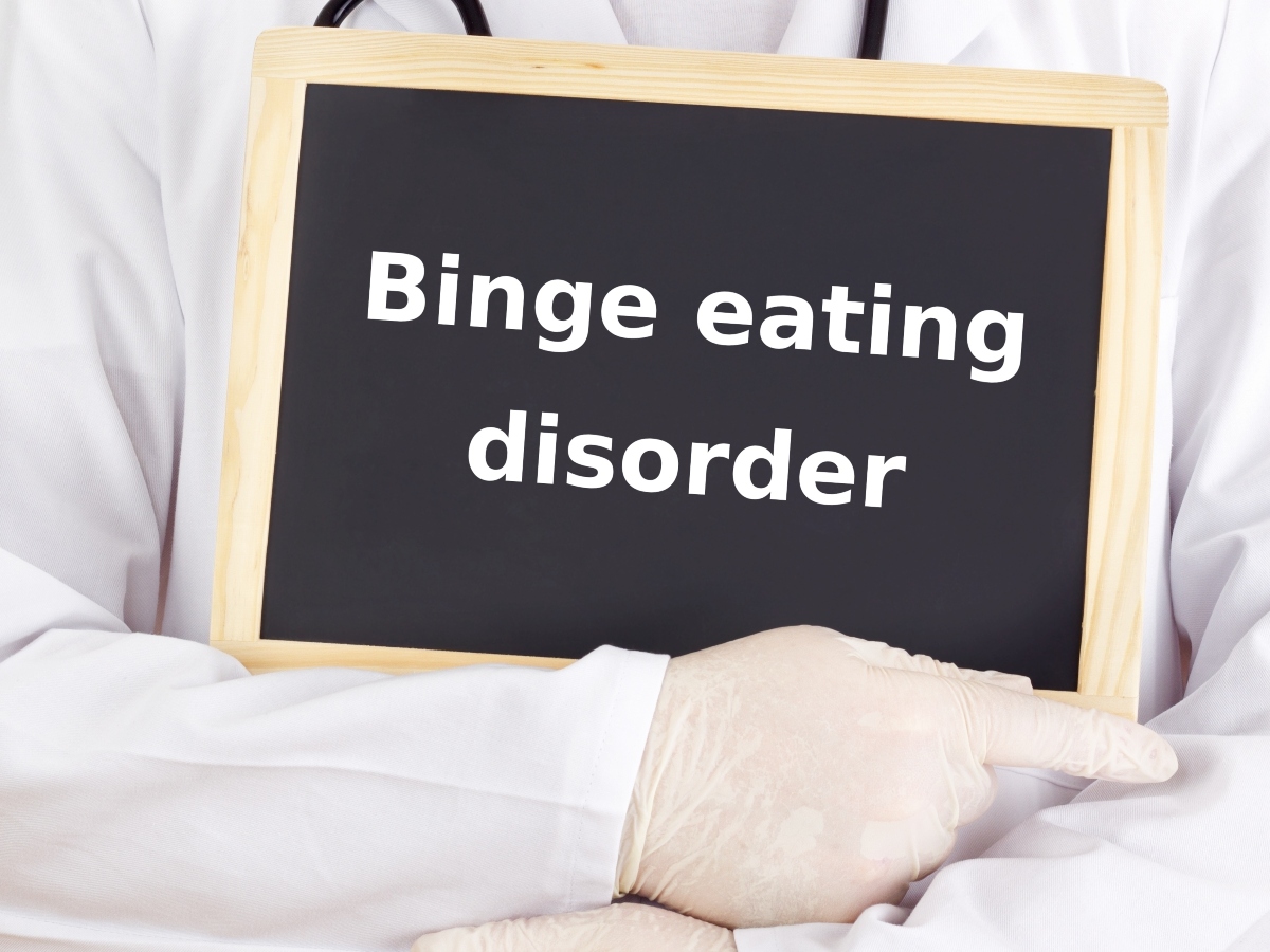 Binge eating: che vuol dire, come si manifesta e come curare il disturbo da alimentazione incontrollata 1 una lavagna in primo piano con la scritta binge eating disorders